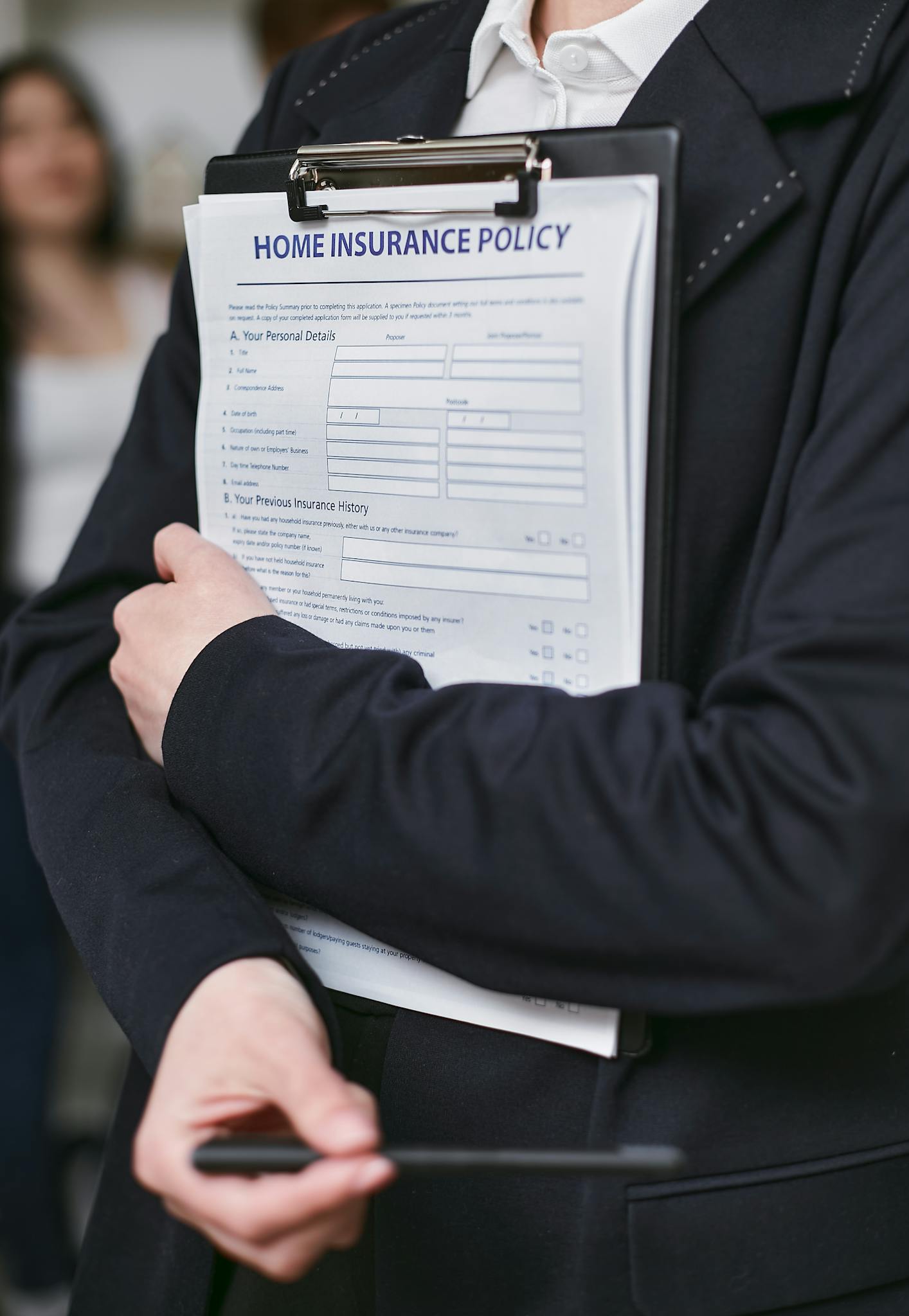 Close-up of a person holding a home insurance policy on a clipboard indoors.